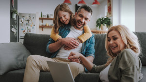 Frau, Mann und Kind mit Laptop auf dem Sofa